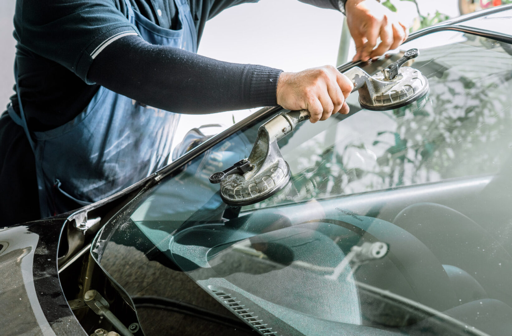 Mechanics man changing the broken windshield and automobile windshield or windscreen replacement of white car in Auto Repair Shop