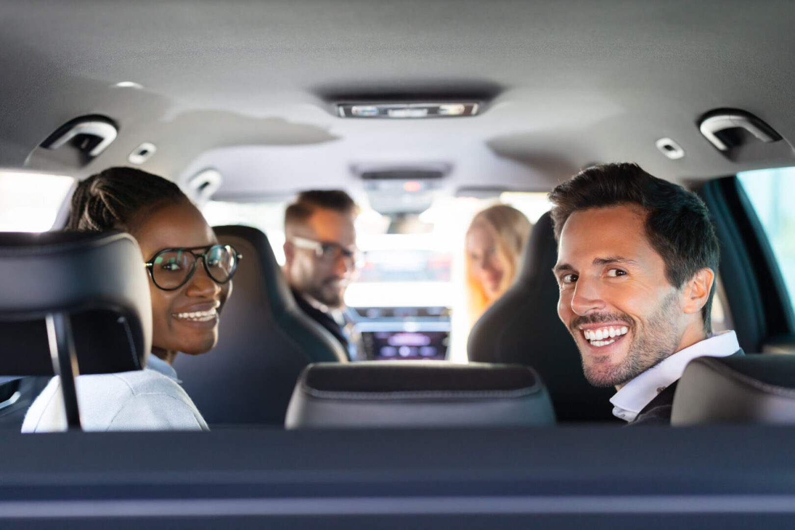 Group Of Cheerful Multi Racial Friends Sitting In Car Enjoying Road Trip Travel